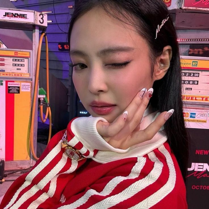 Jennie winking in a red and white outfit